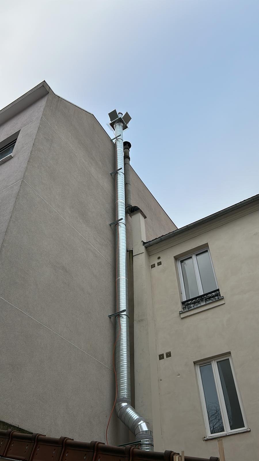 Conduit d'extraction vertical en inox sur façade d'immeuble parisien