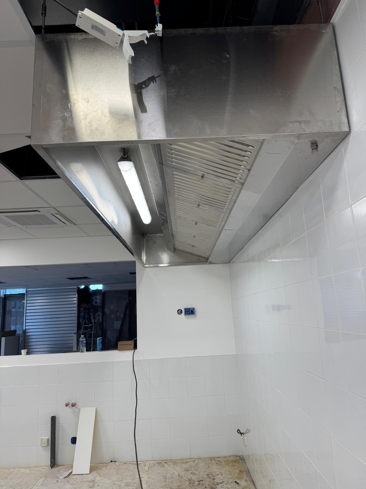 Hotte inox avec filtres à graisse en cuisine professionnelle — chantier