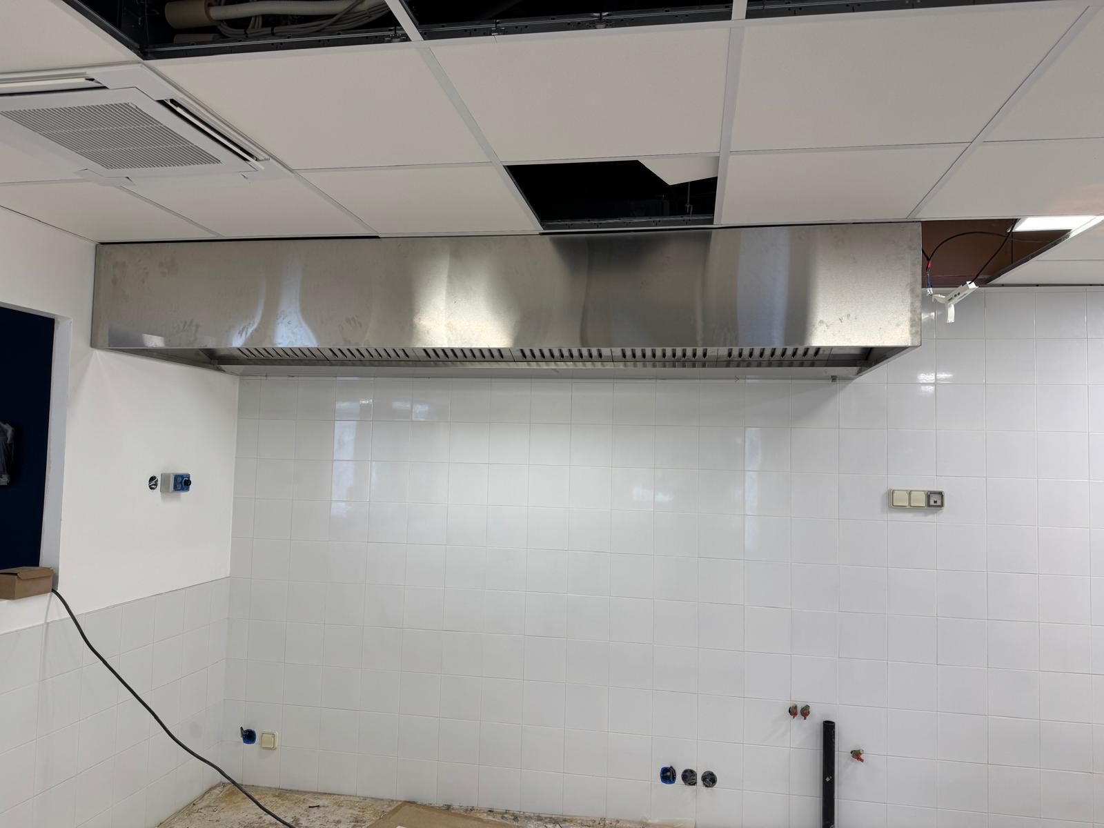 Grande hotte inox murale installée en cuisine collective